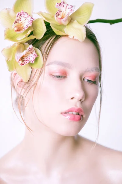 Beautiful young girl with a creative make-up and orchid in her hair. Spring fashion makeup