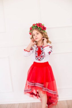 Parlak bir stüdyoda ulusal bir Ukrayna kostümü sarışın kıvırcık saçlı küçük sevimli kız