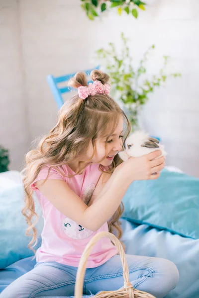 小可爱的女孩与长卷发在床上与小兔子和复活节装饰在家里 — 图库照片