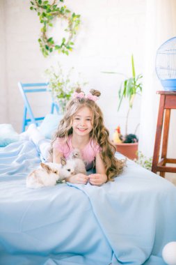 Evde küçük bunnies ve Paskalya dekor ile yatakta uzun kıvırcık saçlı küçük sevimli kız.