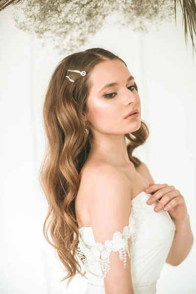 美丽的年轻新娘在一个明亮的工作室与美丽的装饰的白色礼服 — 图库照片