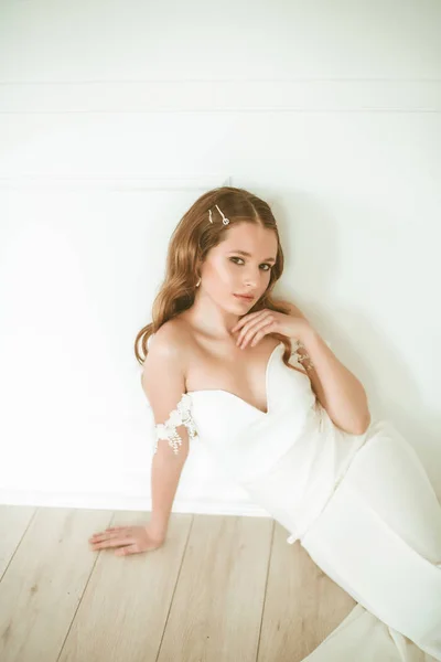 美丽的年轻新娘在一个明亮的工作室与美丽的装饰的白色礼服 — 图库照片