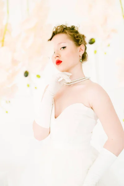 年轻美丽的新娘穿着80年代风格的白色礼服 嘴唇上涂着红色唇膏和兰花 — 图库照片