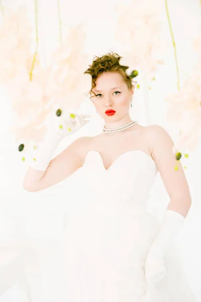 年轻美丽的新娘穿着80年代风格的白色礼服 嘴唇上涂着红色唇膏和兰花 — 图库照片