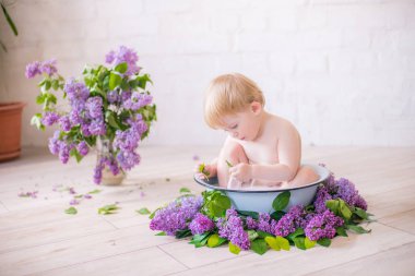 Leylak çiçekleri ile antika süt banyosunda bebek çocuk yakın