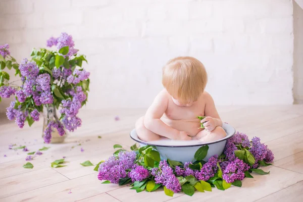 Leylak çiçekleri ile antika süt banyosunda bebek çocuk yakın