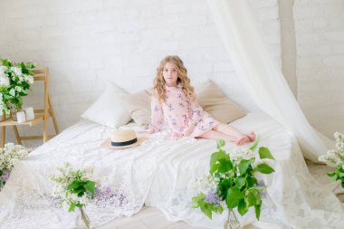 Leylak çiçekleri ile bir bahar stüdyosunda güzel bir elbise sarı saçlı sevimli küçük kız