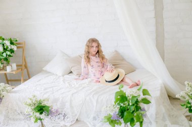 Leylak çiçekleri ile bir bahar stüdyosunda güzel bir elbise sarı saçlı sevimli küçük kız