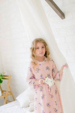 Leylak çiçekleri ile bir bahar stüdyosunda güzel bir elbise sarı saçlı sevimli küçük kız