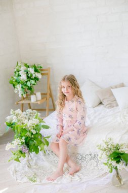 Leylak çiçekleri ile bir bahar stüdyosunda güzel bir elbise sarı saçlı sevimli küçük kız