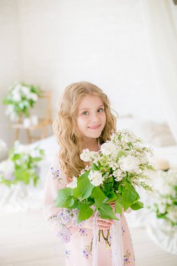 Leylak çiçekleri ile bir bahar stüdyosunda güzel bir elbise sarı saçlı sevimli küçük kız