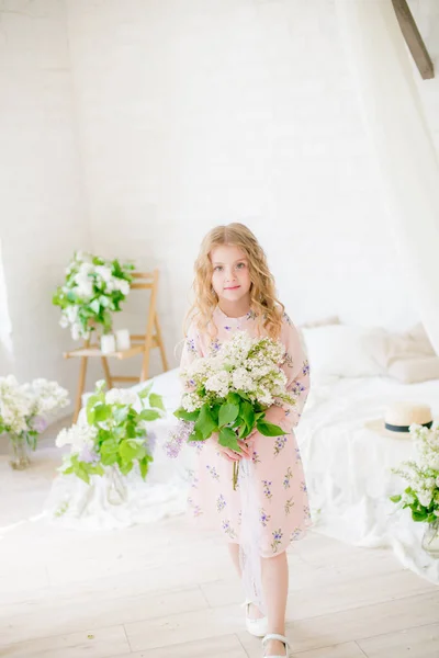 ライラックの花と春のスタジオで美しいドレスでブロンドの髪を持つかわいい女の子 — ストック写真