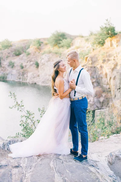 川や湖の近くにエレガントな穏やかなスタイリッシュな新郎新婦 結婚式のカップルで愛 — ストック写真
