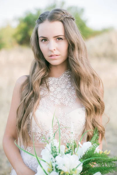 美丽的年轻新娘长头发在婚纱与花束在夏天在外地 — 图库照片