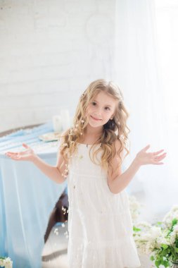 Leylak çiçekleri ile bir bahar stüdyosunda güzel bir elbise sarı saçlı sevimli küçük kız