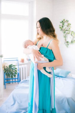 Genç anne ve küçük sevimli bebek mavi yatak örtüsü ve yastıklarla evde yatıyorlar.