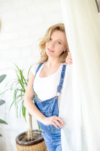 美丽的孕妇 穿着白色T恤和蓝色牛仔裤 在一个房间里有很多活的绿色植物 幸福母亲的概念 健康的生活方式 — 图库照片