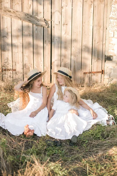 可爱的小女孩与金发长发在夏天的田野在日落的白色礼服与草帽 — 图库照片
