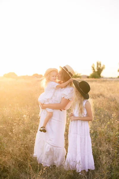 若いです母とともにブロンドの髪の娘白いドレスで夏の日没田舎の分野で — ストック写真
