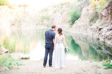 Nehir ya da göl kenarında zarif kibar bir gelin ve damat. Aşık düğün çifti 