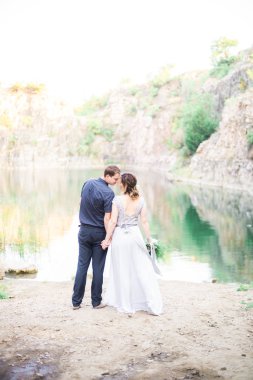 Nehir ya da göl kenarında zarif kibar bir gelin ve damat. Aşık düğün çifti 