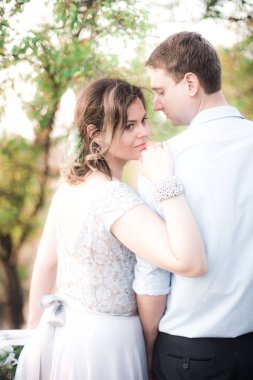 Zarif nazik şık damat ve gelin yaz aylarında gün batımında nehir veya göl yakınında. Aşık düğün çift 