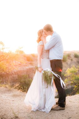 Zarif nazik şık damat ve gelin yaz aylarında gün batımında nehir veya göl yakınında. Aşık düğün çift 