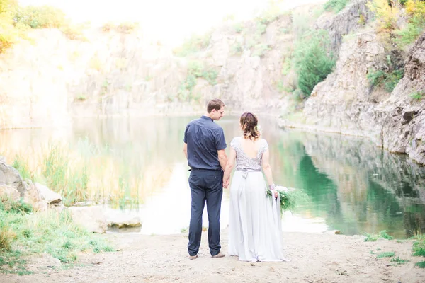 川や湖の近くにエレガントな穏やかなスタイリッシュな新郎新婦 結婚式のカップルで愛 — ストック写真