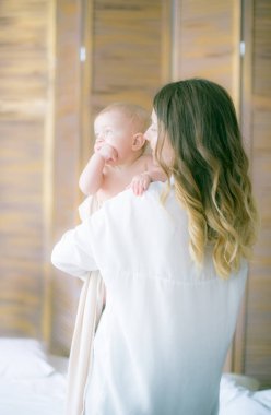 Mutlu bir aile. Anne yatak odasında bebeğiyle oynuyor.