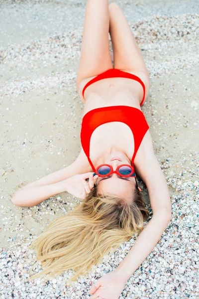 赤い水着で長い髪を持つ美しい若い女の子は晴れた暑い日に海のビーチでリラックス — ストック写真
