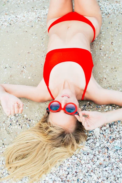 一个美丽的年轻女孩 长头发的红色泳衣放松在阳光明媚的炎热天在海边的海滩上 — 图库照片