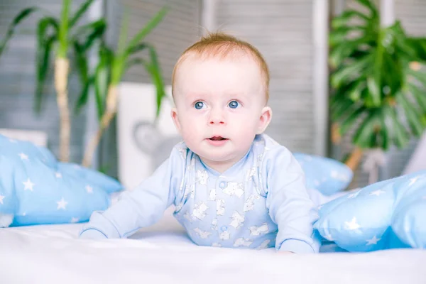 可爱的幼儿男孩在家里的床上周围的蓝色枕头 — 图库照片