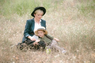 Bir şapkalı küçük çocuk ve yaz aylarında parkta annesi gün batımı