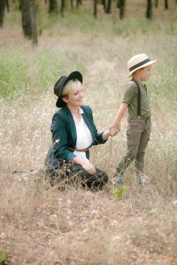 Bir şapkalı küçük çocuk ve yaz aylarında parkta annesi gün batımı