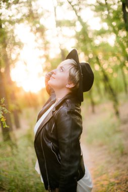 Gün batımı yaz aylarında parkta siyah bir şapka ve deri ceket kız