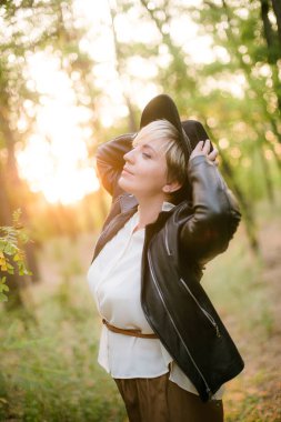 Gün batımı yaz aylarında parkta siyah bir şapka ve deri ceket kız