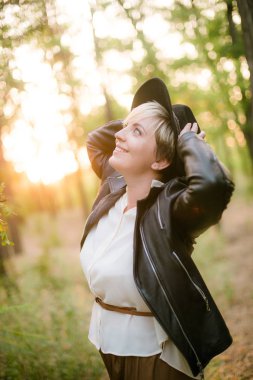 Gün batımı yaz aylarında parkta siyah bir şapka ve deri ceket kız