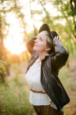 Gün batımı yaz aylarında parkta siyah bir şapka ve deri ceket kız