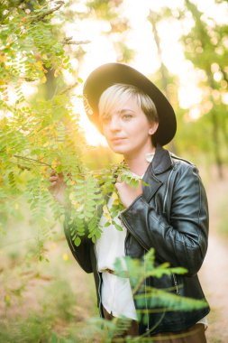 Gün batımı yaz aylarında parkta siyah bir şapka ve deri ceket kız