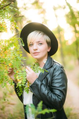 Gün batımı yaz aylarında parkta siyah bir şapka ve deri ceket kız