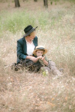 Bir şapkalı küçük çocuk ve yaz aylarında parkta annesi gün batımı