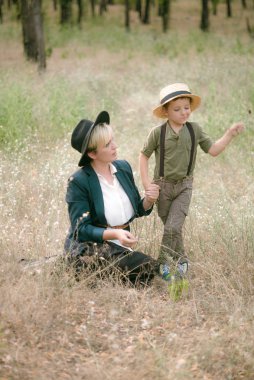 Bir şapkalı küçük çocuk ve yaz aylarında parkta annesi gün batımı