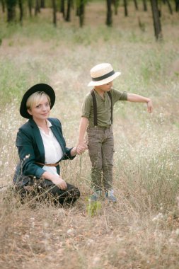 Bir şapkalı küçük çocuk ve yaz aylarında parkta annesi gün batımı