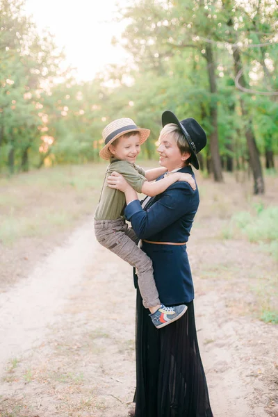 Little boy in a hat and his mom in the park in summer at sunset