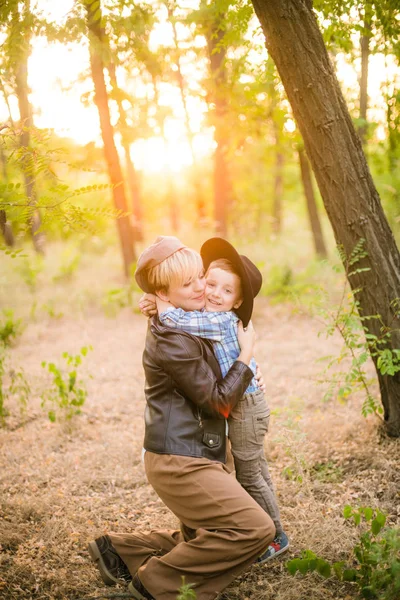 Little boy in a hat and his mom in the park in summer at sunset