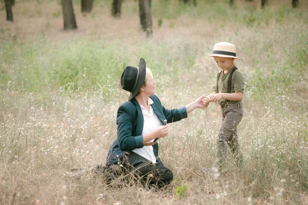 Little boy in a hat and his mom in the park in summer at sunset