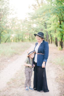 Bir şapkalı küçük çocuk ve yaz aylarında parkta annesi gün batımı