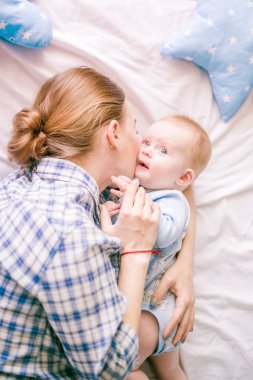 Gömlek ve mavi jeans erkek bebek onun yatak - görüntü ile oynarken güzel anne portresi