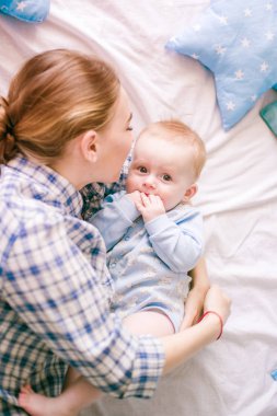 Gömlek ve mavi jeans erkek bebek onun yatak - görüntü ile oynarken güzel anne portresi