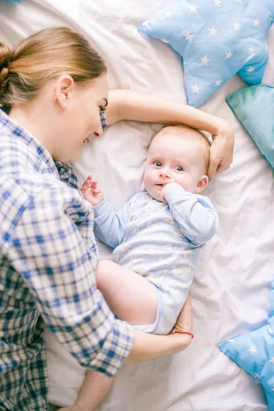 シャツとブルー ジーンズ イメージの寝室で彼女の男の子と遊ぶ美しいお母さんの肖像画 — ストック写真